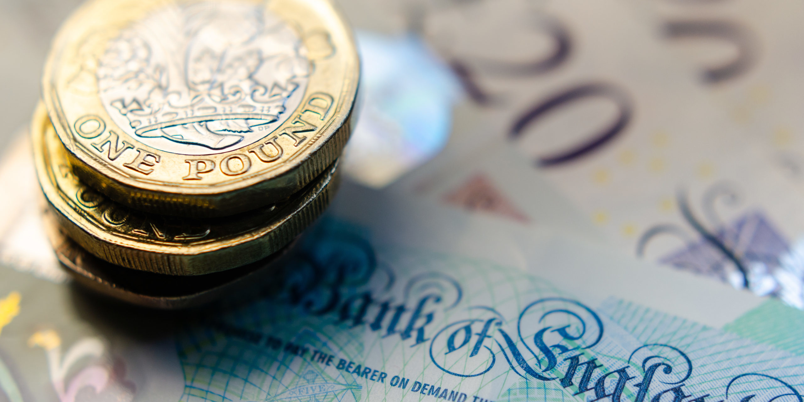 British money. Macro photo of One Pound coins and the British pound banknotes of different denomination.