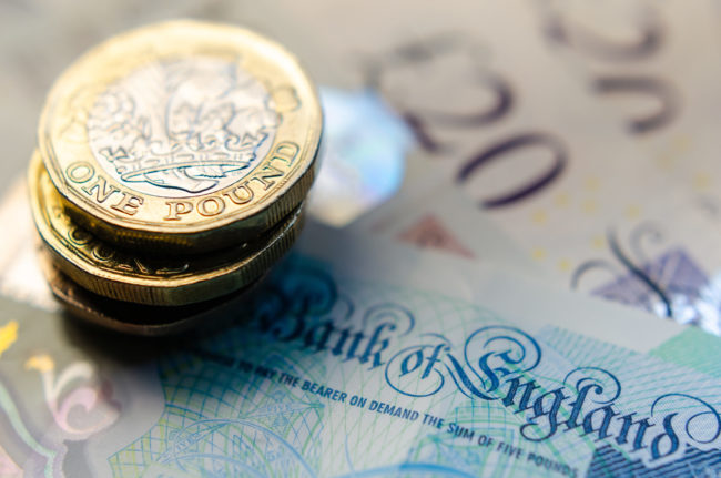 British money. Macro photo of One Pound coins and the British pound banknotes of different denomination.
